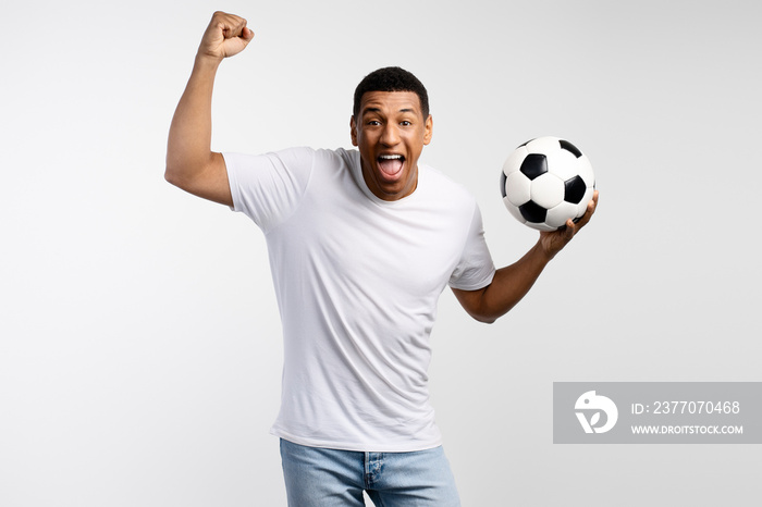 Portrait of handsome man holding soccer ball at his hands with smiling positive expression