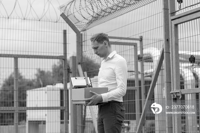 The businessman got out of prison with his things and is thinking about what to do next. A man stands near the exit from the prison.