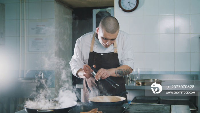 The cook adds spices to food