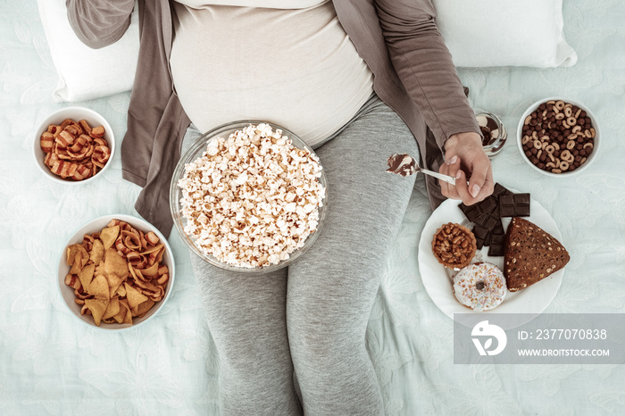 Pregnant woman in comfortable clothes lying in bed