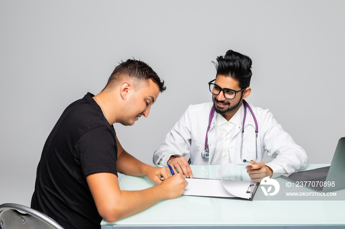 Patient signs a document with his indian doctor in medical office