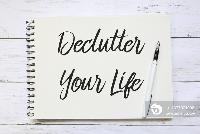 Top view of pen and notebook written with Declutter Your Life on wooden background.