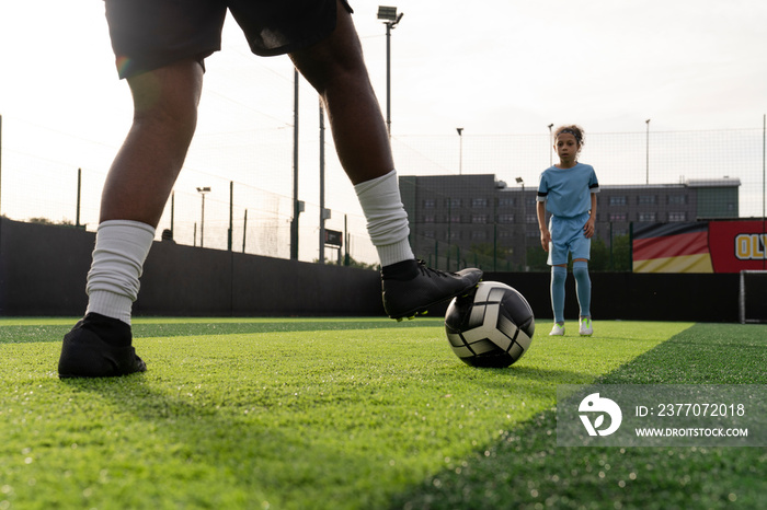 Man and girl (6-7) playing soccer on soccer field