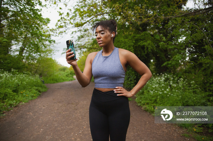 Young curvy woman with vitiligo talking on the phone with earbuds in workout clothes