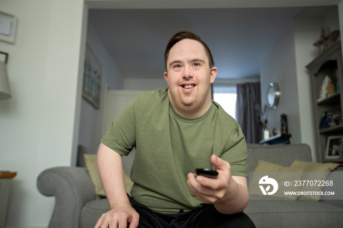 Man sitting on sofa and using remote control