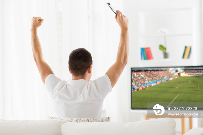 happy man watching football or soccer game on tv