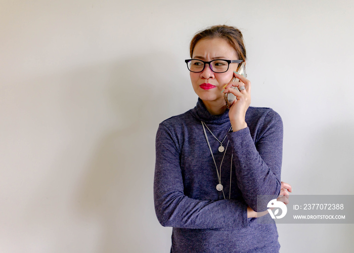 Angry Asian business woman talking on cell phone. Isolated on white.