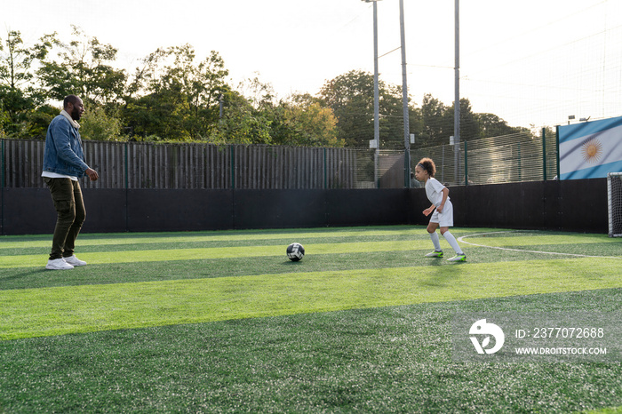 Father and daughter (6-7) playing soccer on soccer field