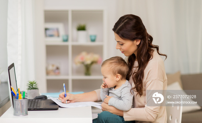 happy mother with baby and papers working at home