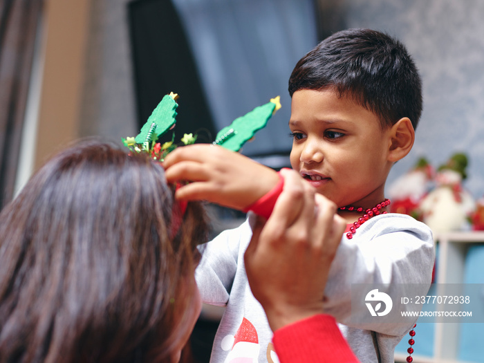 Boy putting Christmas headband on mother