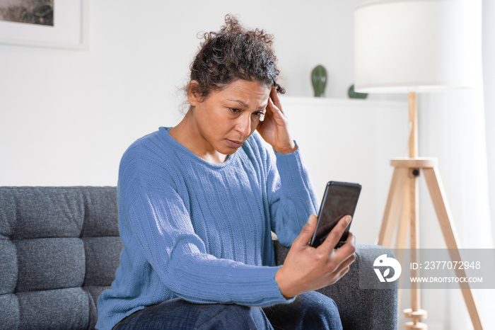 Sad black woman reading bad news on smart phone