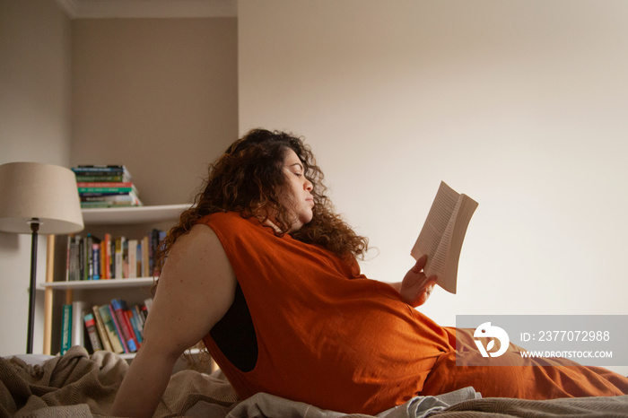 Plus-sized Sri Lankan woman with vitiligo reading in her bedroom