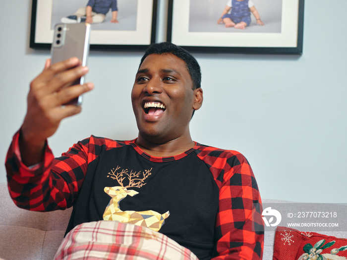 Smiling man having video call via smart phone in bed