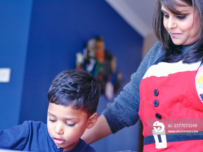 Woman in Christmas apron looking at son