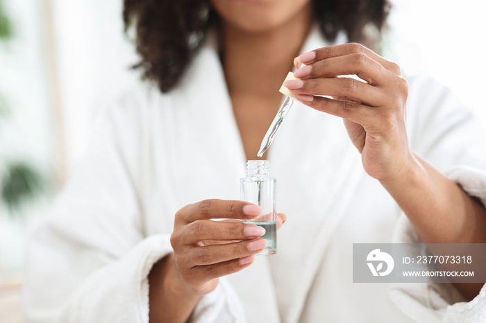 Essential Oils Benefits. Bottle With Organic Serum In Hands Of Black Woman