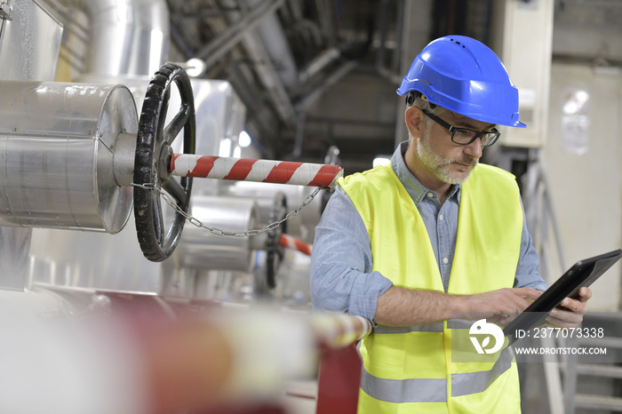 Industrial technician connected with tablet in recyling plant