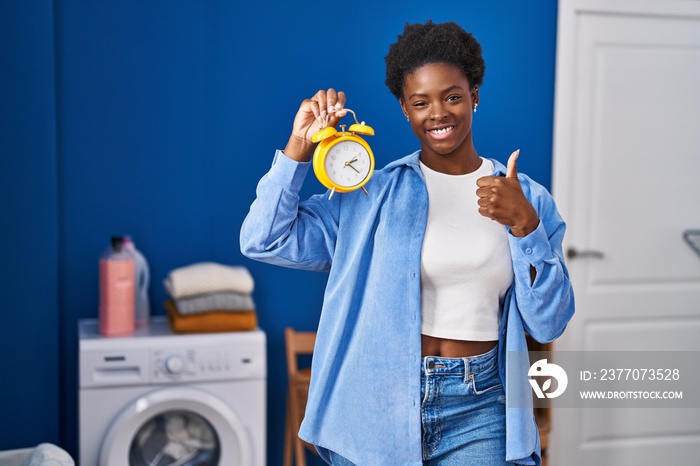 African american woman waiting for laundry smiling happy and positive, thumb up doing excellent and approval sign