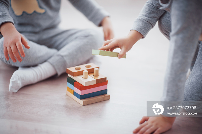 Children play with a toy designer on the floor of the children’s room. Two kids playing with colorful blocks. Kindergarten educational games