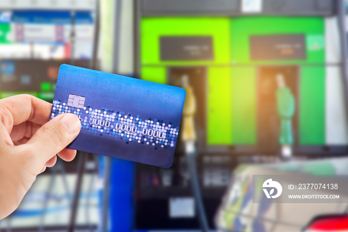 Man use credit card with blur image of gas station as background.(concept don’t use mobile in gas station)