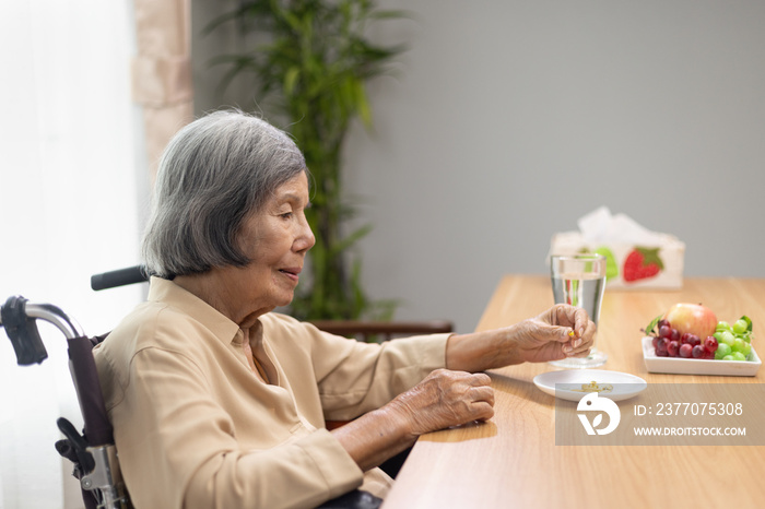 Elderly woman taking fish oil supplements after lunch.