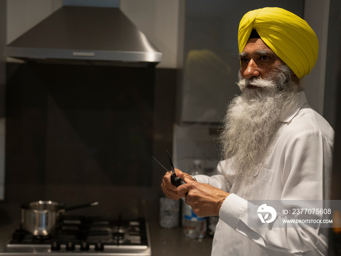 Senior man in turban cooking in kitchen