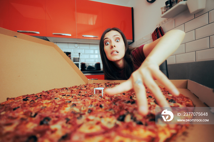 Hungry Craving Woman Reaching for an Enormous Pizza. Gourmand girl having a large snack full of carbs all by herself