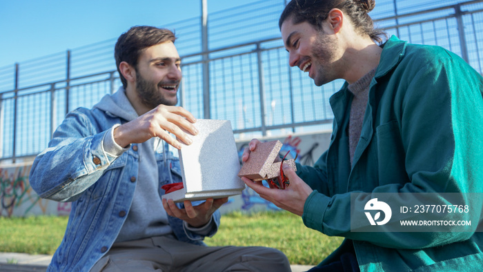 Smiling gay couple opening gift boxes outdoors