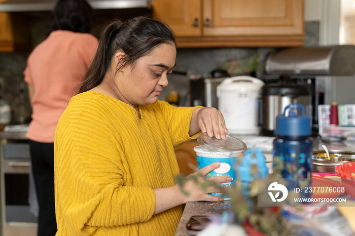 Woman with down syndrome preparing food with mother in kitchen