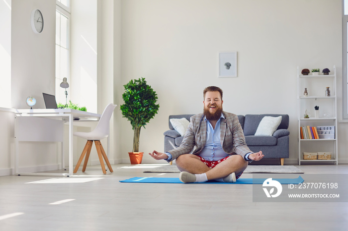 Yoga work at home. Funny fat man practices yoga meditation while sitting on the floor in the room online at home.