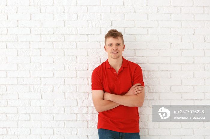 Portrait of handsome young man against white brick wall