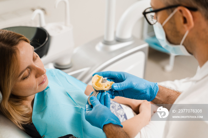 Dentist showing cast of teeth of patient woman before dental implantation. Procedure of creating dental prostheses, crowns and aligners.