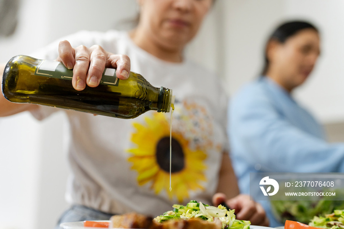 Woman using olive oil for meal, close up