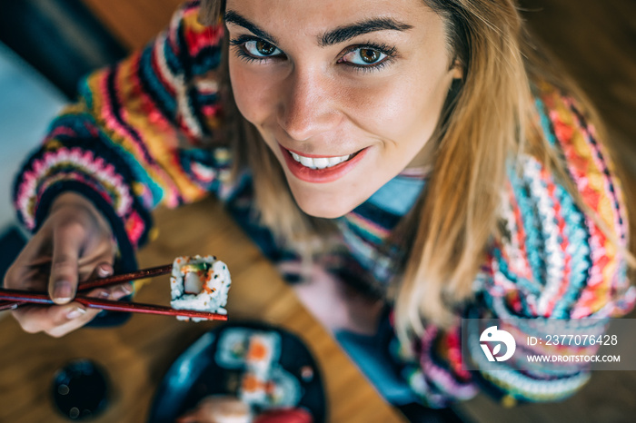 from above Crop woman eating sushi