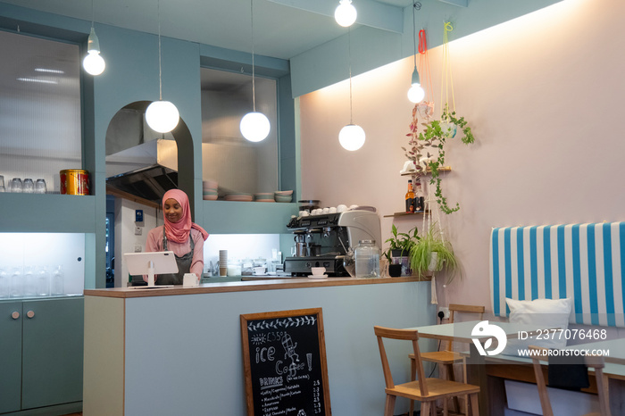 Young woman in hijab working in cafe