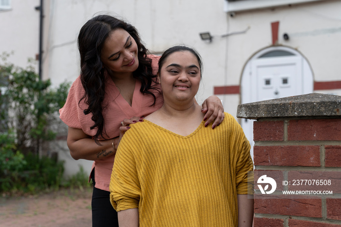 Portrait of woman with down syndrome daughter in front of house