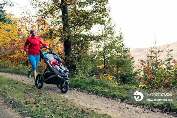 Running mother with stroller enjoying motherhood at autumn sunset