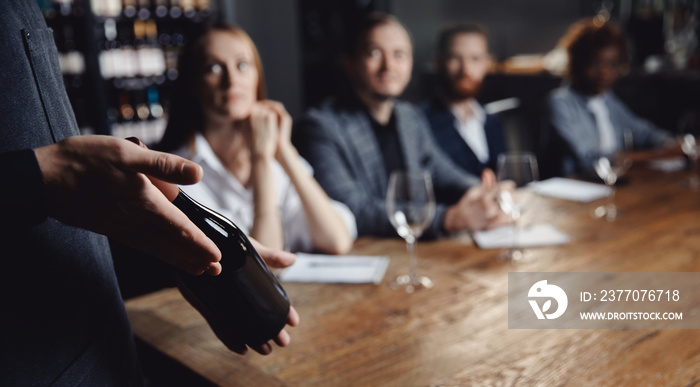 Banner Male sommelier conducts red wine tasting for restaurant guests