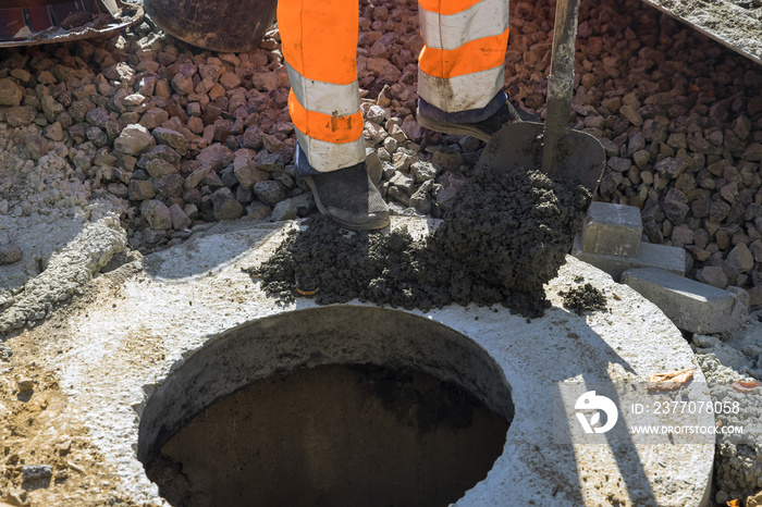 A worker the new road construction work on preparation for installation of sewer hatches