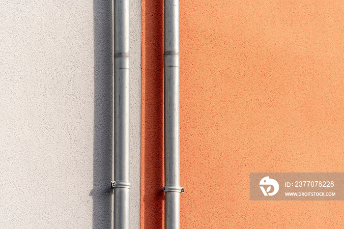 Two drainpipes over grey and terracotta wall with the rule of thirds