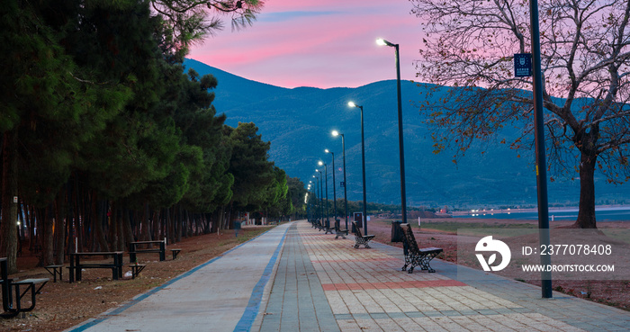 Many street lamp post and cobblestone way with mountain and red color sky background.