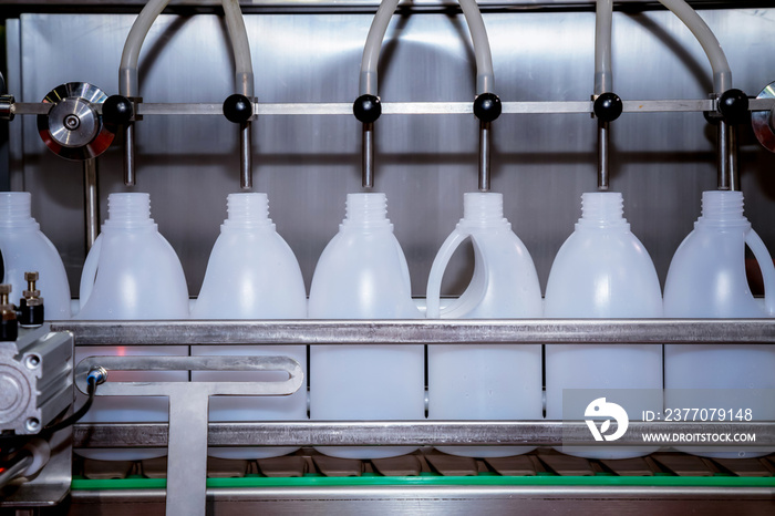 white plastic gallons or bottle on the production line of the conveyor at filling machine in the factory. selective focus. industrial and technology concept.