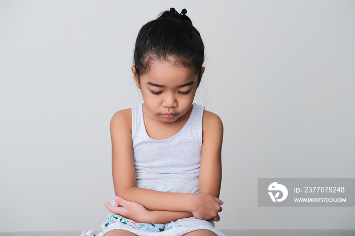 Asian little girl showing sad expression when sitting with her face looking down