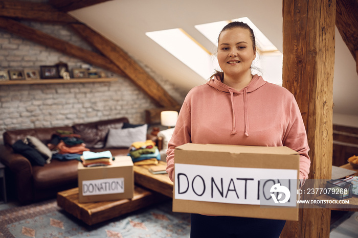 Portrait of happy woman holding donation box and looking at camera.