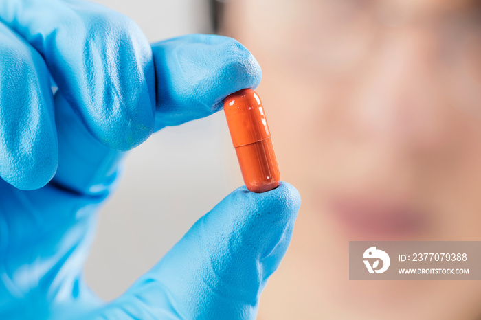 Scientist’s Hand in a Glove Holding an Orange Pill