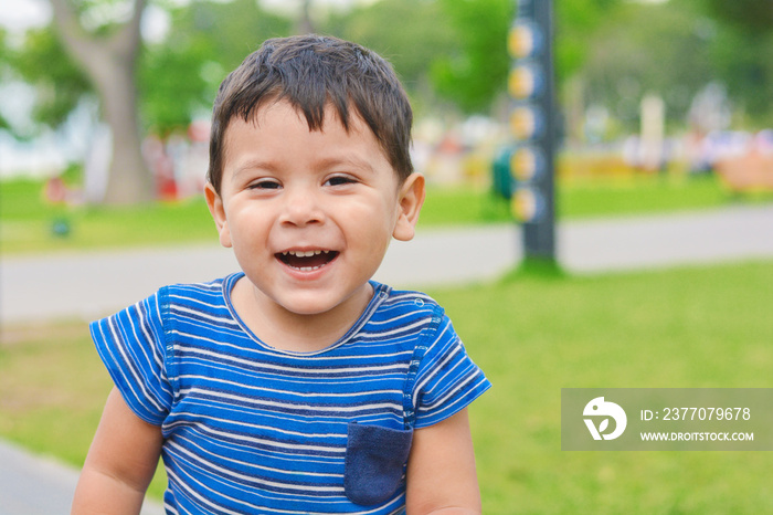 Smiling little latin boy outside.