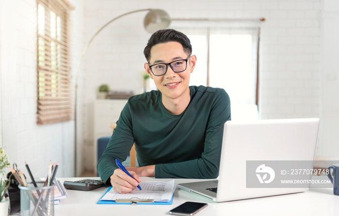 Smiling handsome asian businessman working from home.