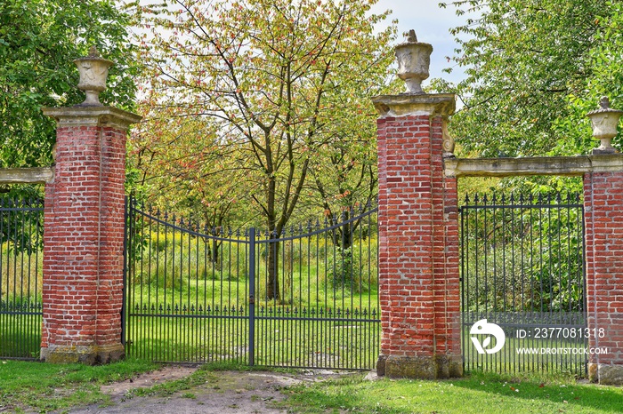 Wrought iron entrance gate to the garden. Brick pillars and sandstone decorations. Westerwinkel castle, North Rhine-Westphalia, Germany