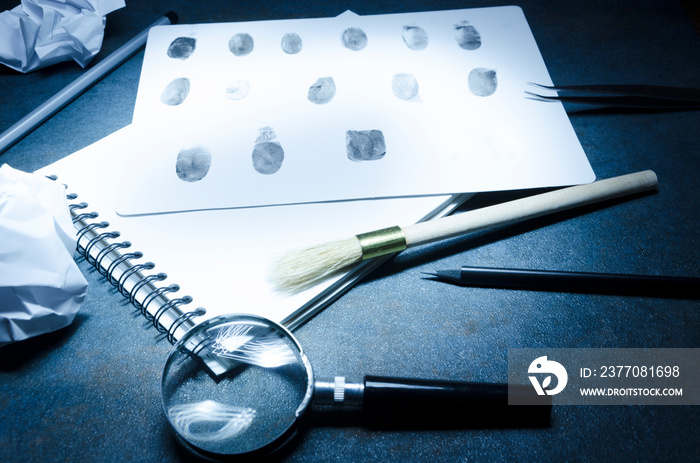 Professional detective`s workplace.Magnifying glass, notebook, fingerprints, special tools on the table