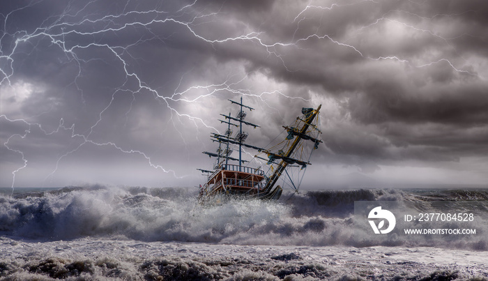 Sailing old ship in storm sea against heavy sunset clouds