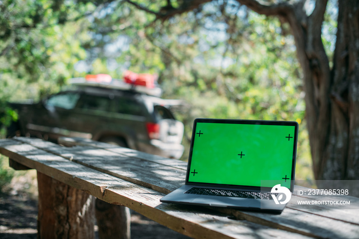 Open laptop on a wooden table in a camping in the mountains